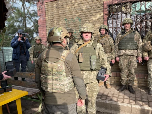 Ukrainian President Volodymyr Zelensky (seen from the back) gives Ukrainian soldiers watches as presents in Shyrokyne