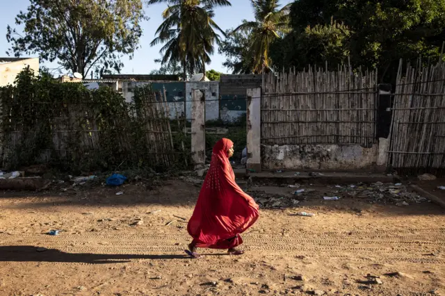 A woman walks along a street in Pemba on May 25, 2021.