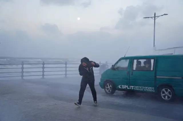 A person fights against the wind on the seafront in Porthcawl, Bridgend, Wales