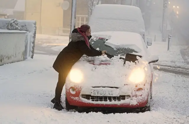 A woman clears snow from her car in Tow Law, County Durham