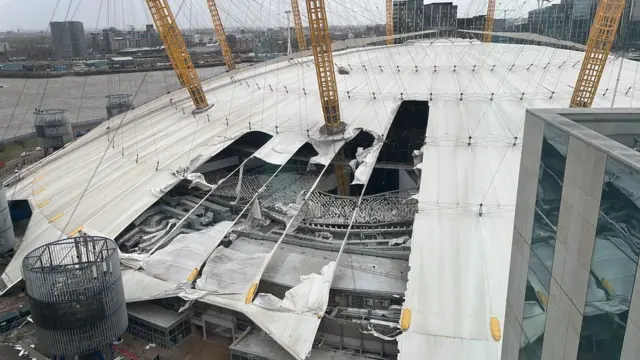 An aerial view of the O2 arena showing sections of the roof missing, with the fabric shredded