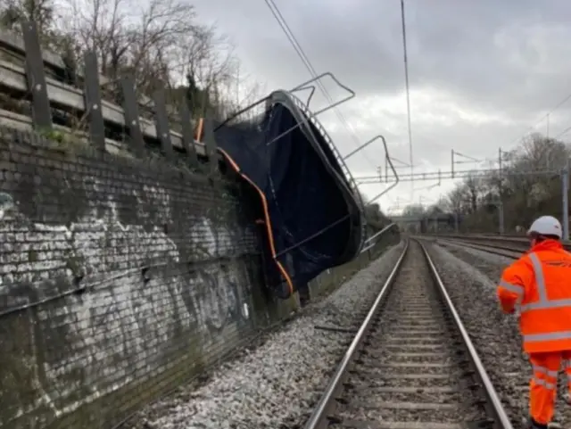 A railway worker inspects a trampoline blown onto the train track