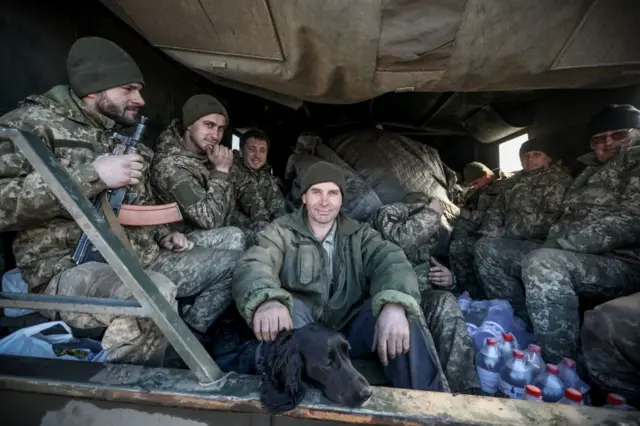 Ukrainian military servicemen sit in the back of a truck in the Donetsk region