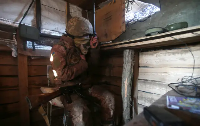 A serviceman of Ukrainian Military Forces looks through spyglass on his position on the front line with Russia backed separatists, near Novognativka village, Donetsk region on February 21, 2022.