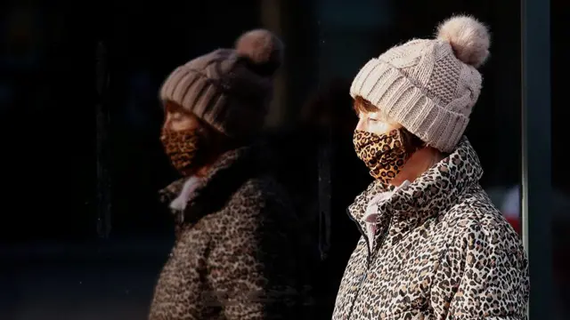 A woman wearing a leopard print face mask and coat