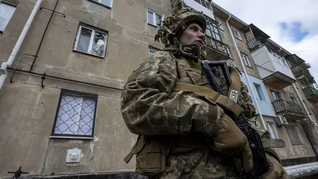 A soldier is seen in front of a building damaged by bullets and cannon balls in Luhansk