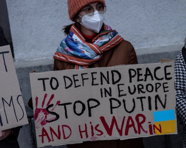 A protester in Kyiv holds a slogan that reads: "To defend peace in Europe stop Putin and his war in Ukraine. Photo: 21 February 2022