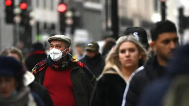 People in street, one man wearing mask