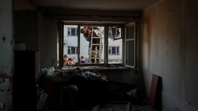 Communal workers look into a destroyed house after yesterday"s shelling near the front line, near the city of Novoluhanske in the Donetsk region, Ukraine