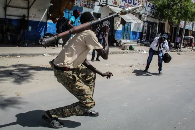 Photographers take pictures of a Somali military force member