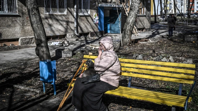 A woman weeps as she sits outside a building that was damaged by bombing in the eastern Ukraine town of Kharkiv