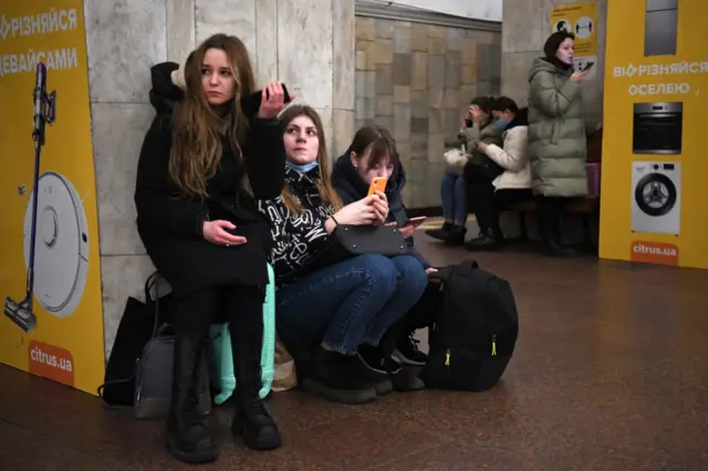 Girls on their phones, taking shelter inside the underground station