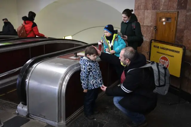 A father reassures his son as his family takes refuge in a metro station