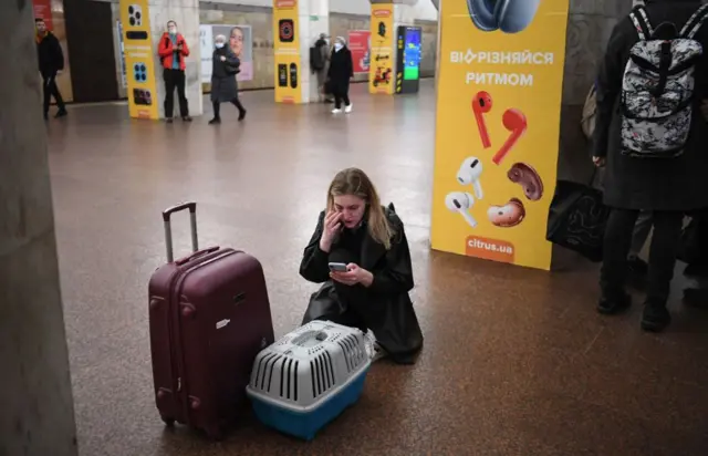 Woman at Kyiv metro station with suitcase and cat carrier