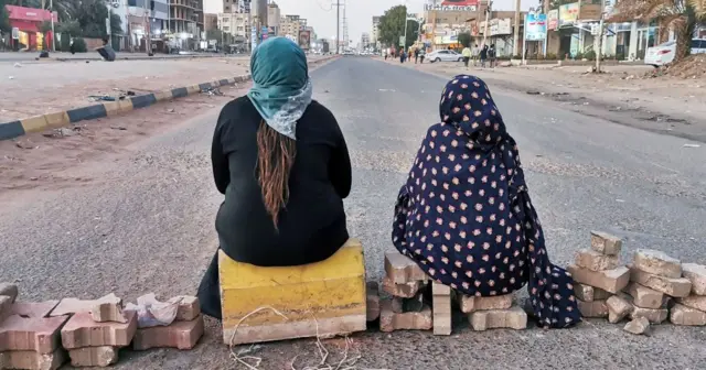 Two protesters sit on a brick barricade in Sudan