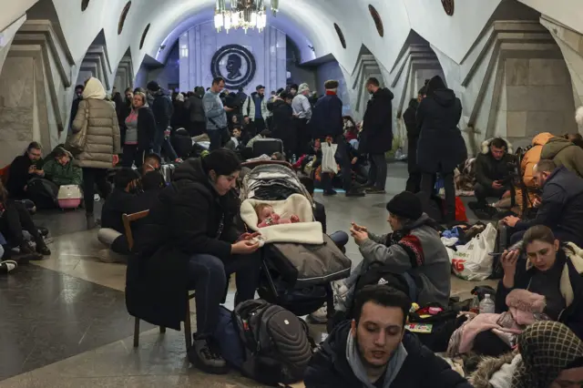 Dozens of people standing and sitting while taking shelter in underground metro station in Kharkiv, Ukraine