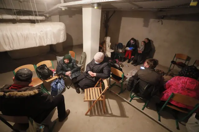 Group of people sitting on chairs and dressed in warm clothing in underground metro station in Kyiv, Ukraine