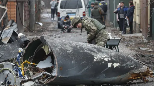 A soldier inspects the remains of a plane shot down over the Ukrainian capital, Kyiv