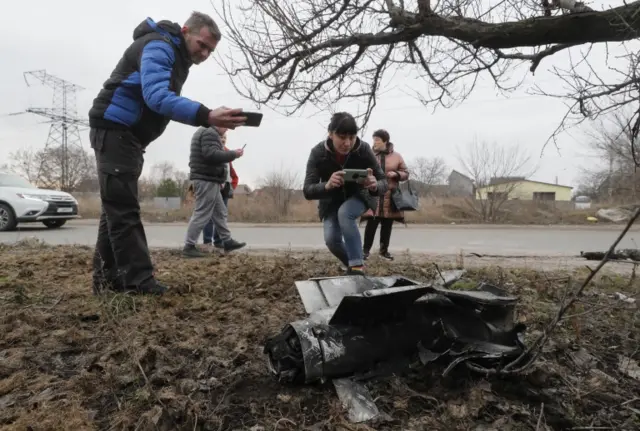 People take pictures of the debris of a rocket on the street after overnight shelling in Kyiv