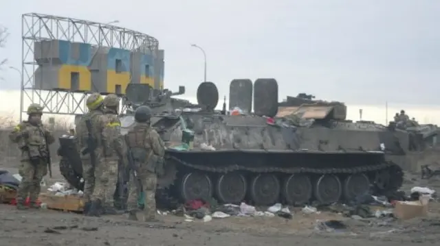 Ukrainian servicemen stand next to an armoured vehicle in Kharkiv