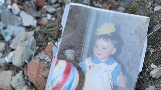 A photograph of a child in rubble