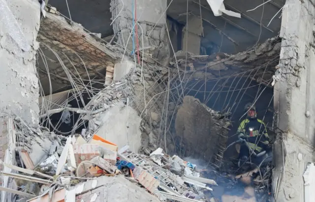 A firefighter works inside an apartment building damaged by recent shelling in Kyiv, Ukraine