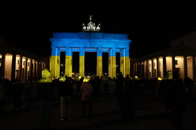 People take pictures in front of the Brandenburg Gate enlightened with the colors of Ukraine in Berlin, Germany on February 23, 2022