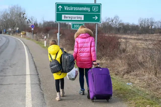 A Ukrainian mother and daughter walk along the road from the Hungarian-Ukrainian border