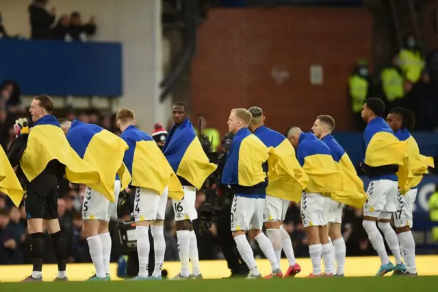 Everton players line up with Ukraine flags