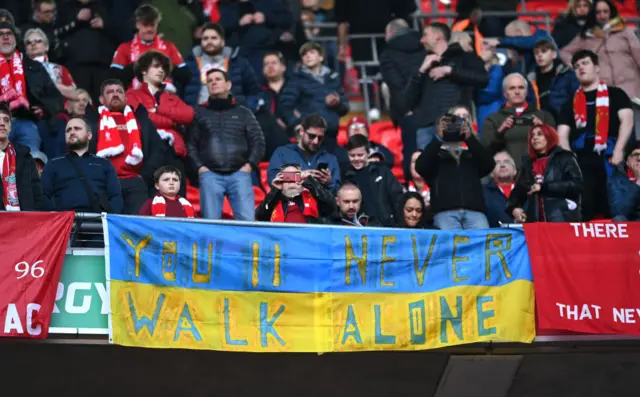 A banner saying You'll Never Walk Alone on Ukrainian flags