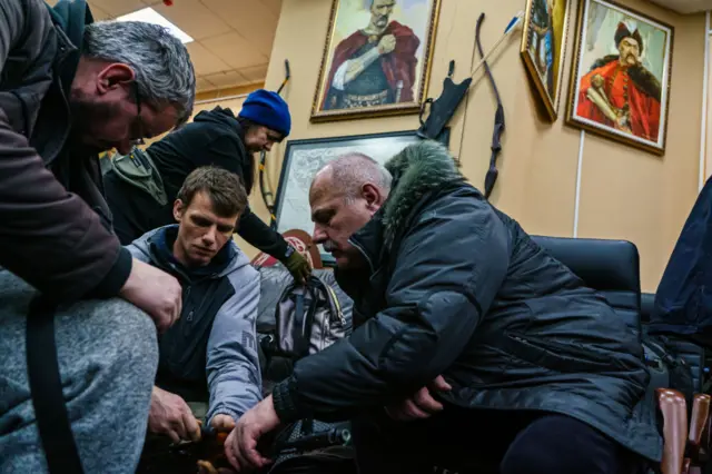 Men at a volunteer army branch in Kyiv gather as they collect and prepare their weapons in an Kyiv bunker.