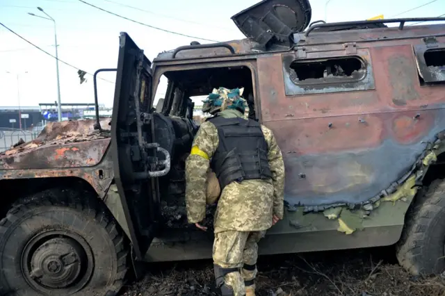 An Ukrainian Territorial Defence fighter examines a destroyed Russian infantry mobility vehicle GAZ Tigr after the fight in Kharkiv on February 27, 2022. -