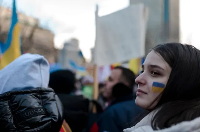 A woman looks on as members of the Ukrainian community protest at Place du Canada in Montreal, Quebec, on February 27, 2022