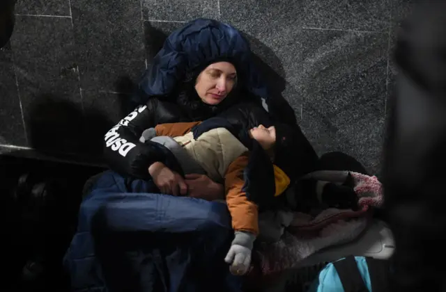 A mother watches her child sleep at Lviv train station in Western Ukraine on February 26, 2022.