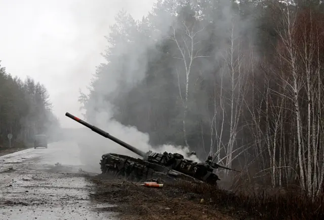 A destroyed Russian tanks smouldering on a Ukrainian road