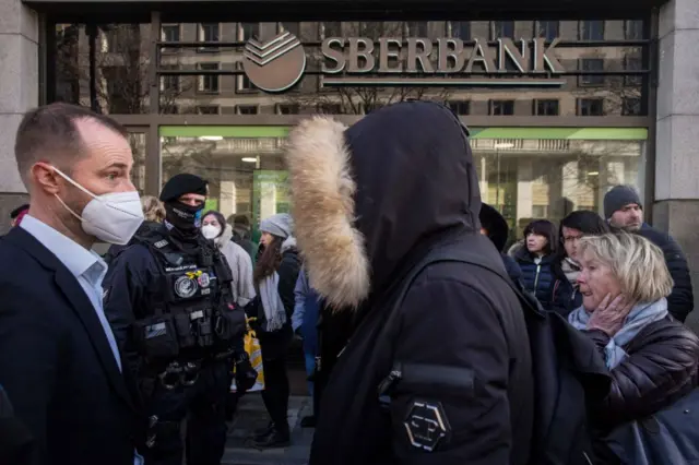 People queue outside a branch of Russian state-owned bank Sberbank to withdraw their savings and close their accounts in Prague on February 25, 2022, before Sberbank will close all its branches in the Czech Republic later in the day.