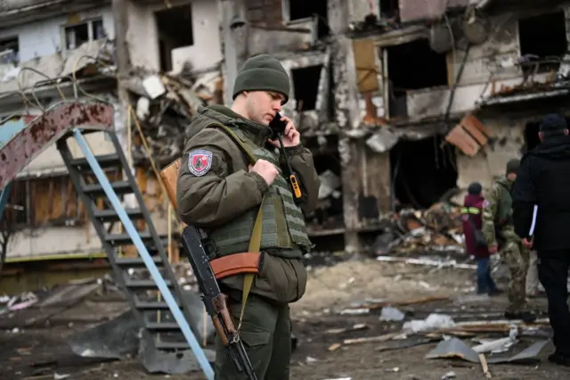 A Ukrainian serviceman uses his phone in a Kyiv suburb