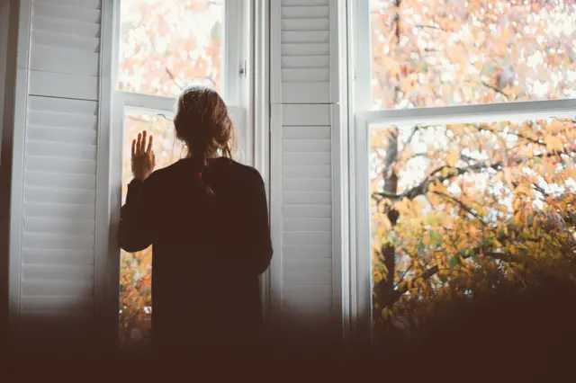 Stock image of a woman looking out of a window