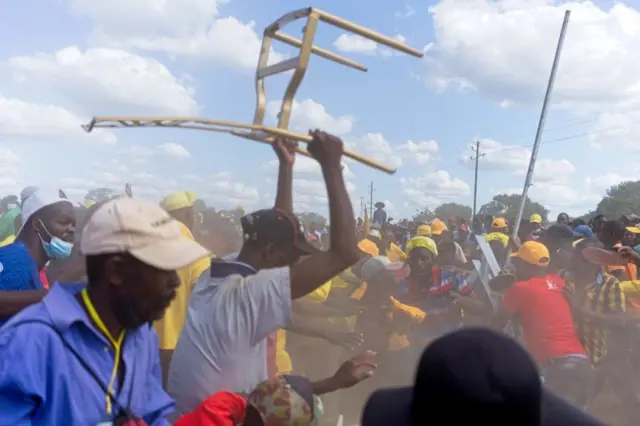 A n alleged supporter of the ruling ZANU-PF brandishes a chair as he attacks supporters of the opposition Citizens Coalition for Change during their electoral rally on February 27, 2022