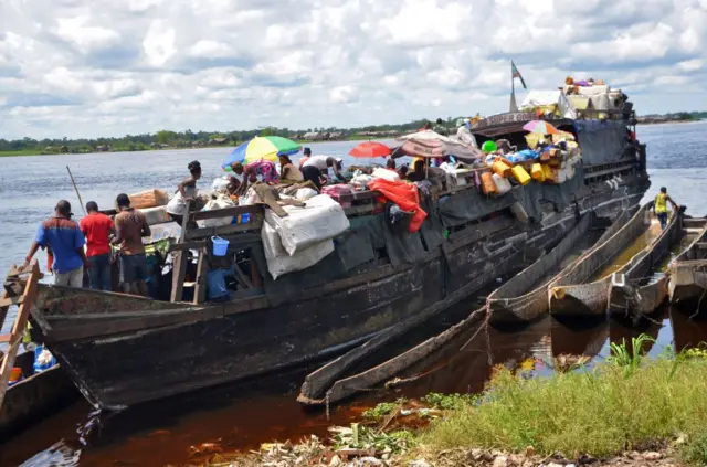 Passengers and merchants embark on a barge on the Congo river