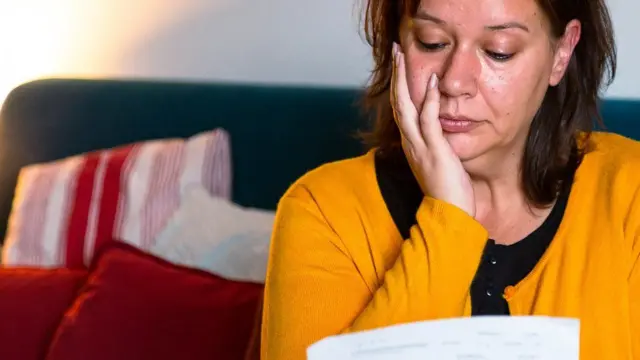 A woman reads a bill