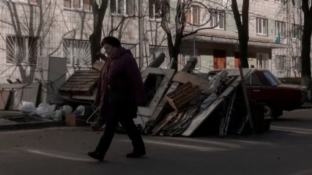 A woman walks past a street barricade in Kyiv, Ukraine (28 February 2022)