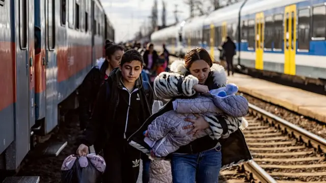 A family holding a baby walking next to a train