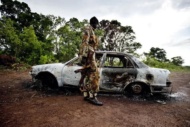 A soldier walks past a burnt vehicle in South Sudan's Western Equitoria State