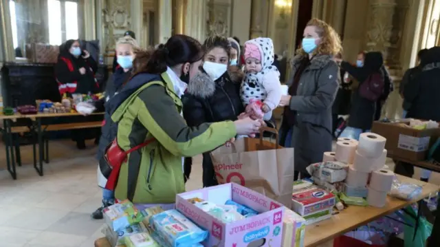 A Ukrainian refugee and her daughter receive foods and sanitary items at an aid point in Budapest.