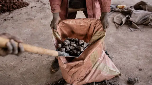 A miner fills a bag with cobalt