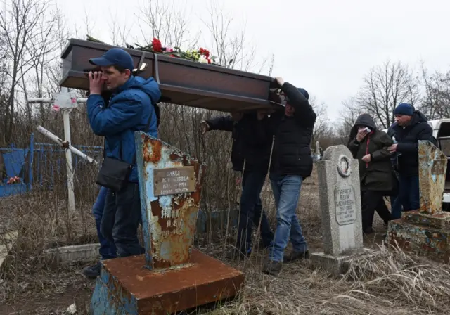 Men carry the coffin of a school teacher