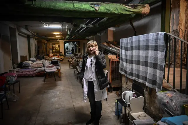 A doctor speaks on the phone as she stands in the newly located pediatrics center after it were moved to the basement of the hospital which is being used as a bomb shelter, in Kyiv