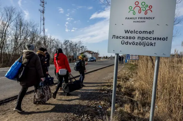 People walk with their belongings at the Astely-Beregsurany border crossing