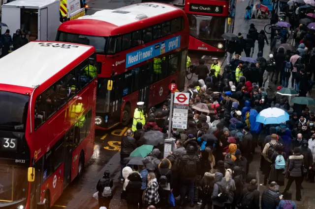 People wait to get on buses at Liverpool Street station